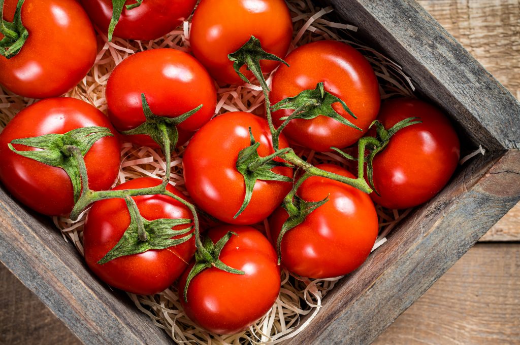 Tomates rondes rouges dans une caisse en bois.