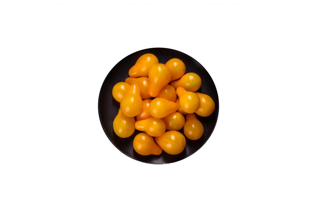 Tomates cerises poires jaunes dans un saladier noir.