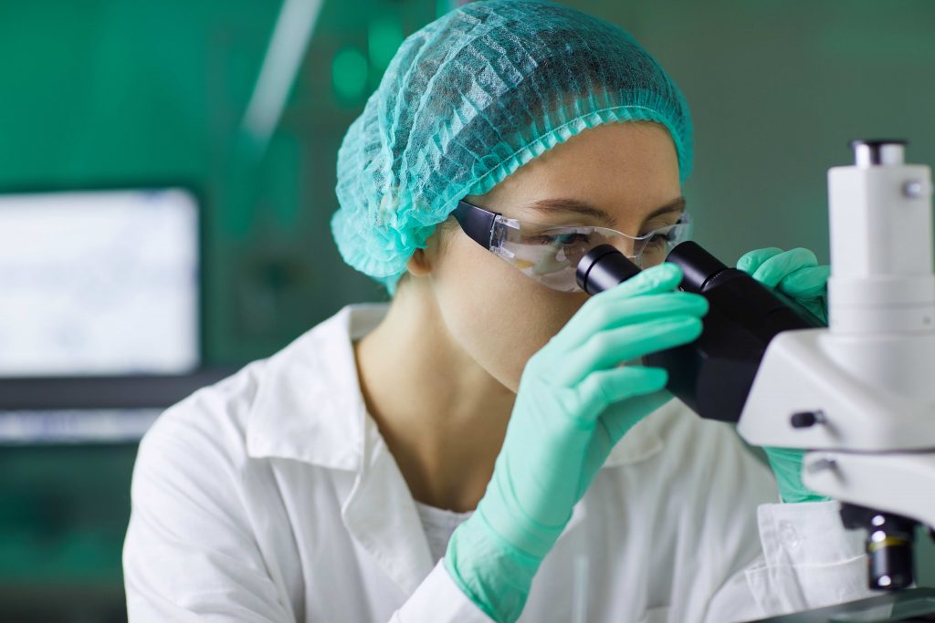 recherches médicales microscope, une femme avec des lunettes et des gants verts