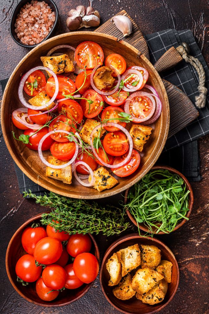 Salade de tomates avec des croutons de pain, herbes aromatiques fraiches et oignons rouges.
